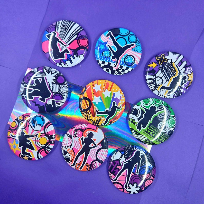 May include: A collection of eight circular pin-back buttons featuring vibrant, multi-colored graphic designs. Each button displays a black silhouette of a person in a dynamic pose set against abstract patterns, geometric shapes, and bright color palettes.