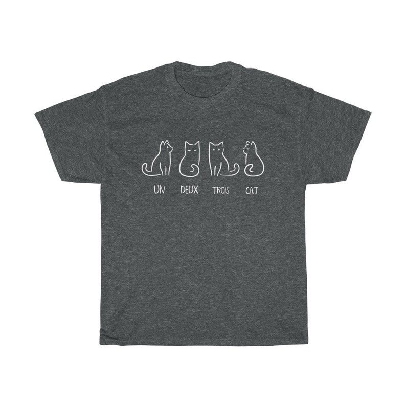 May include: Dark gray t-shirt featuring a white line drawing of four cats in different poses. Below the cats, the text reads "UN DEUX TROIS CAT". The shirt is made of a soft, comfortable material.