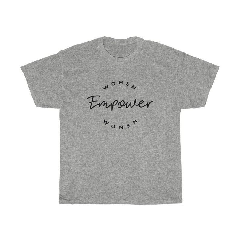 May include: A heather gray t-shirt with the words "Women Empower Women" in black script and a circular font. The shirt is a crew neck style and has short sleeves. The text is centered on the front of the shirt.