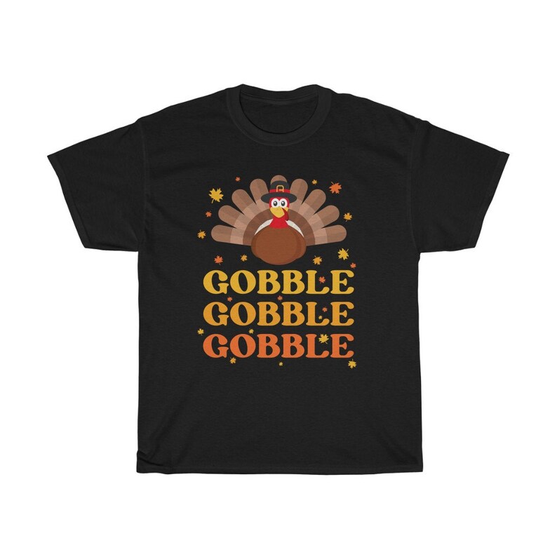 May include: Black t-shirt featuring a Thanksgiving turkey illustration with a pilgrim hat and autumn leaves. The words "GOBBLE GOBBLE GOBBLE" are printed in yellow and orange below the turkey design.
