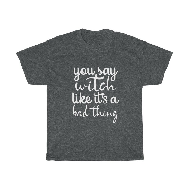 May include: Dark gray t-shirt with the white text "you say witch like it's a bad thing". The shirt has a crew neck and short sleeves. The text is in a handwritten style font.