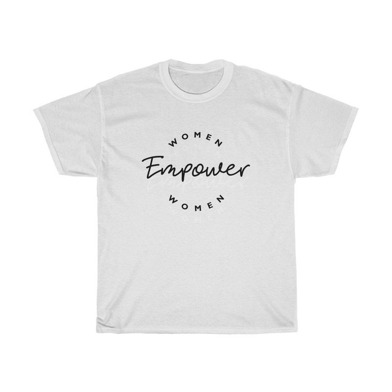 May include: White t-shirt with the text "WOMEN Empower WOMEN" in a black, circular design. The shirt is a crew neck style and appears to be made of a soft, comfortable material. The text is in a handwritten style font.