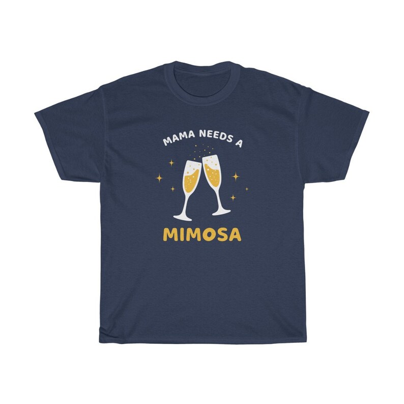 May include: Navy blue t-shirt with the text "MAMA NEEDS A MIMOSA" in white and yellow. The design features two champagne flutes with bubbly liquid and star accents. A casual, comfortable tee.