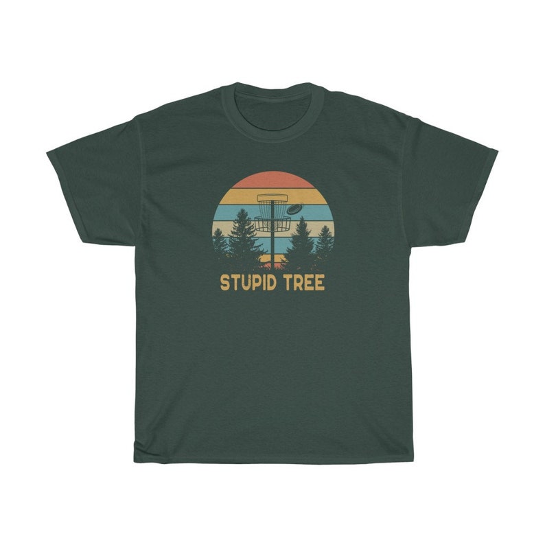 Pode incluir: T-shirt verde escuro com um design retr&ocirc; com uma cesta de disc golf, &aacute;rvores e um p&ocirc;r do sol. O texto "STUPID TREE" est&aacute; abaixo do gr&aacute;fico. A camisa &eacute; feita de um material macio e confort&aacute;vel.