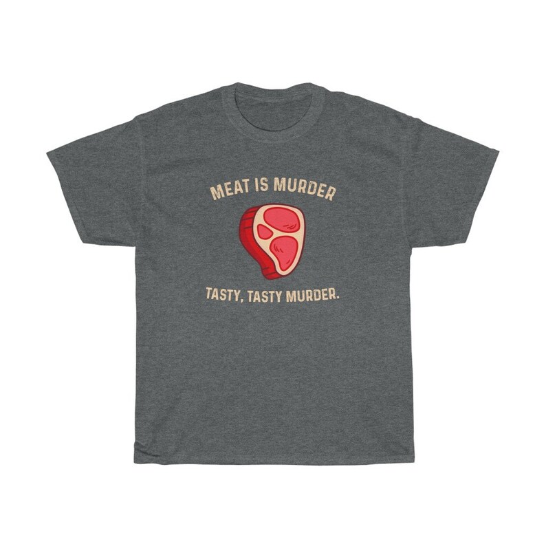 Op de afbeelding: Donkergrijs t-shirt met de tekst "MEAT IS MURDER" boven een cartoon steak illustratie. Onder de illustratie staat de tekst "TASTY, TASTY MURDER".