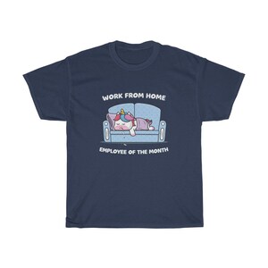 K&ouml;nnte beinhalten: Marineblaues T-Shirt mit einem Cartoon-Einhorn, das auf einem blauen Sofa schl&auml;ft. Das Einhorn hat eine bunte M&auml;hne und ist mit einer lila Decke bedeckt. Der Text "WORK FROM HOME EMPLOYEE OF THE MONTH" steht dar&uuml;ber und darunter.