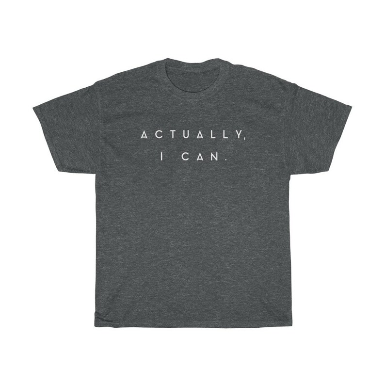 Op de afbeelding: Donkergrijs t-shirt met de tekst "ACTUALLY, I CAN." in het wit. Het shirt heeft een ronde hals en korte mouwen. De stof lijkt een zacht, comfortabel materiaal te zijn.