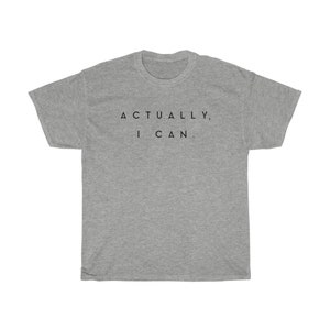 Op de afbeelding: Een grijs t-shirt met de zwarte tekst "ACTUALLY, I CAN.". De top met korte mouwen heeft een ronde hals en is gemaakt van een zachte stof.