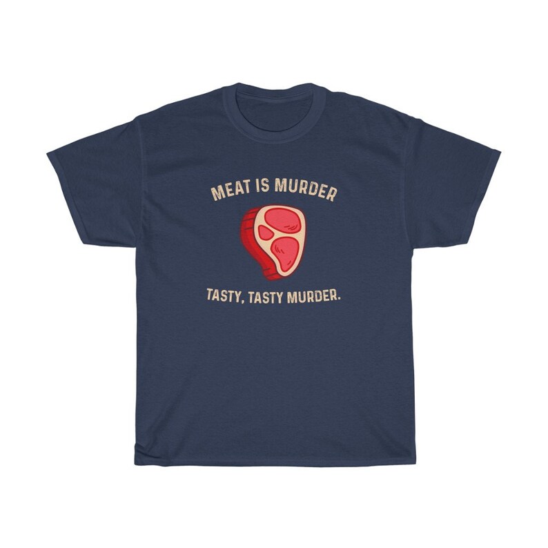 Op de afbeelding: Marineblauwe t-shirt met de tekst "MEAT IS MURDER" boven een cartoon steak illustratie. Onder de illustratie staat de tekst "TASTY, TASTY MURDER".