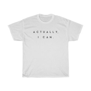 Op de afbeelding: Een wit t-shirt met de zwarte tekst "ACTUALLY, I CAN.". Het t-shirt heeft korte mouwen en een ronde hals. De tekst is gecentreerd op de voorkant van het t-shirt.