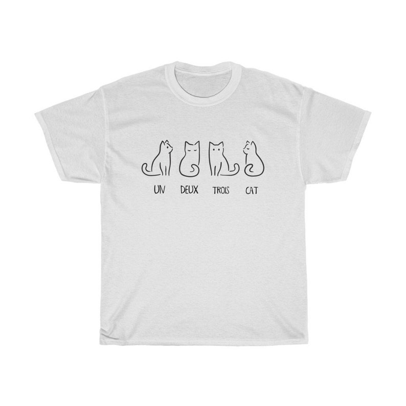 May include: White t-shirt featuring a minimalist design of four black cat illustrations. Below the cats, the words "UN DEUX TROIS CAT" are printed in black. The shirt is made of a soft, comfortable material.