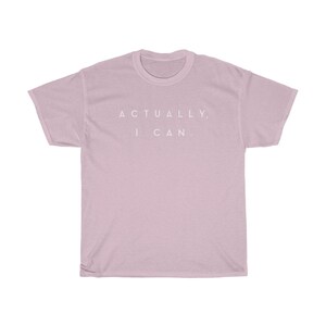 Op de afbeelding: Lichtroze t-shirt met de witte tekst "ACTUALLY, I CAN." gecentreerd op de borst. Het shirt heeft korte mouwen en een ronde hals.
