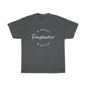 May include: Dark gray t-shirt with the words "WOMEN Empower WOMEN" in white script and block letters. The text is arranged in a circular design. The shirt is made of a soft material.