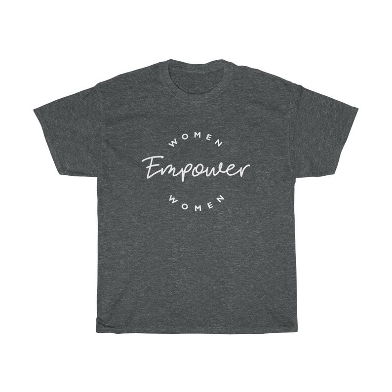 May include: Dark gray t-shirt with the words "WOMEN Empower WOMEN" in white script and block letters. The text is arranged in a circular design. The shirt is made of a soft material.