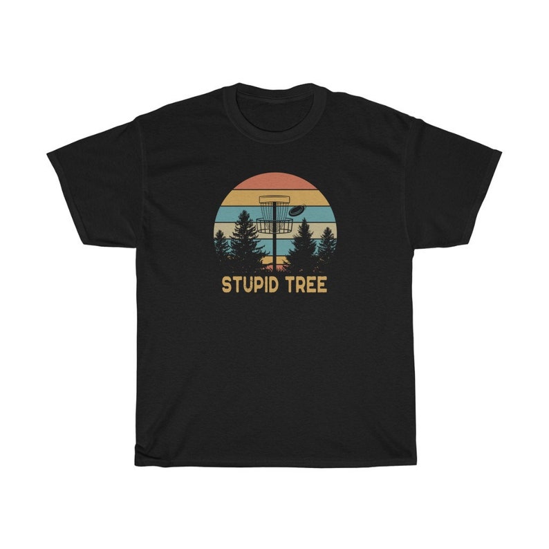Pode incluir: Camiseta preta com um design retr&ocirc; com uma cesta de disc golf, um disco voador e pinheiros contra um p&ocirc;r do sol. O texto "STUPID TREE" est&aacute; abaixo.