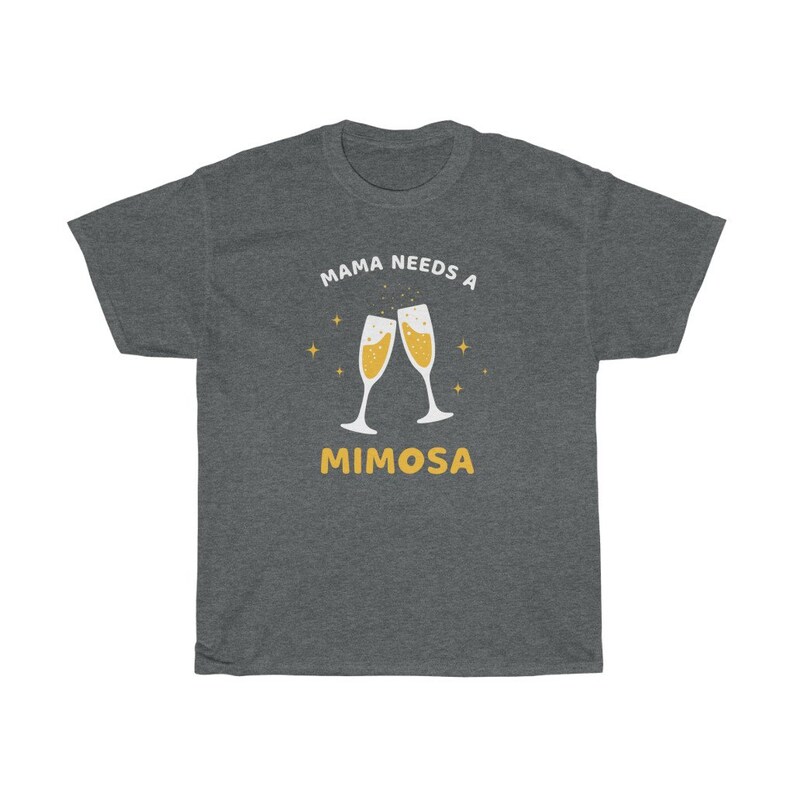 May include: Dark gray t-shirt with the text "MAMA NEEDS A MIMOSA" in white and yellow. The design features two champagne flutes with bubbly liquid and star accents. A casual, comfortable tee.