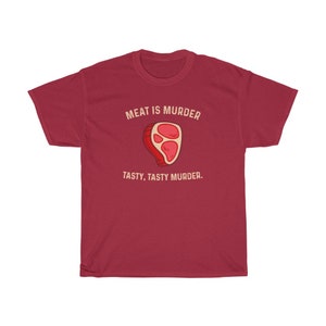 Op de afbeelding: Een bordeauxrood t-shirt met de tekst "MEAT IS MURDER" boven een cartoon steak illustratie. Onder de illustratie staat de tekst "TASTY, TASTY MURDER."
