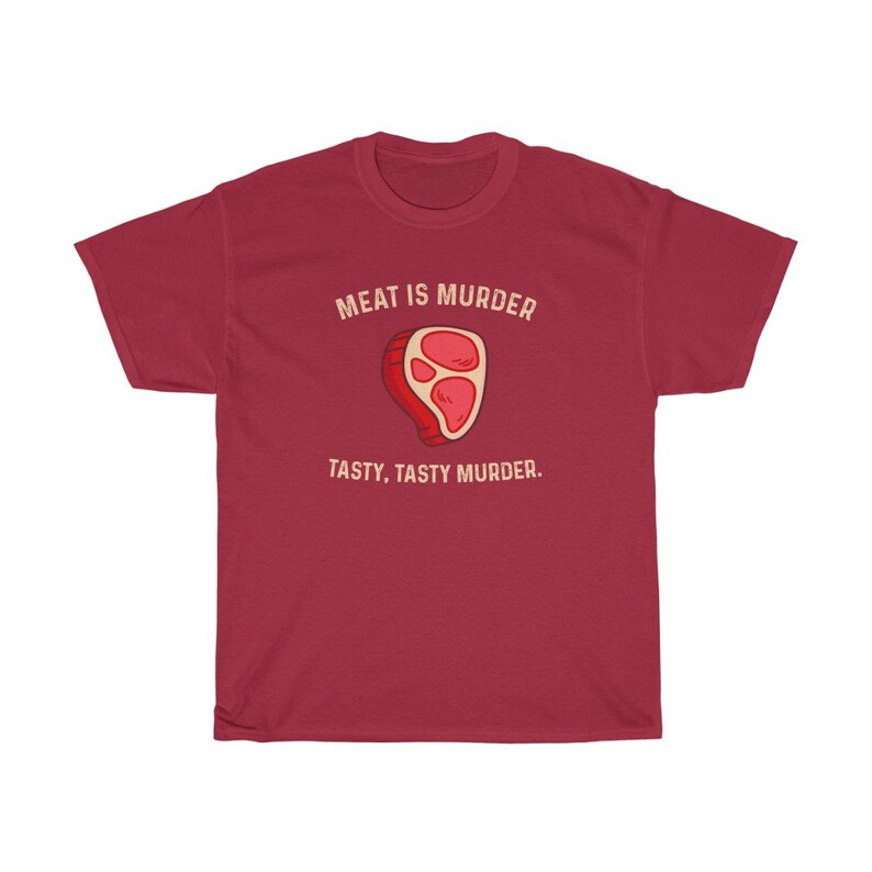 Op de afbeelding: Een bordeauxrood t-shirt met de tekst "MEAT IS MURDER" boven een cartoon steak illustratie. Onder de illustratie staat de tekst "TASTY, TASTY MURDER."