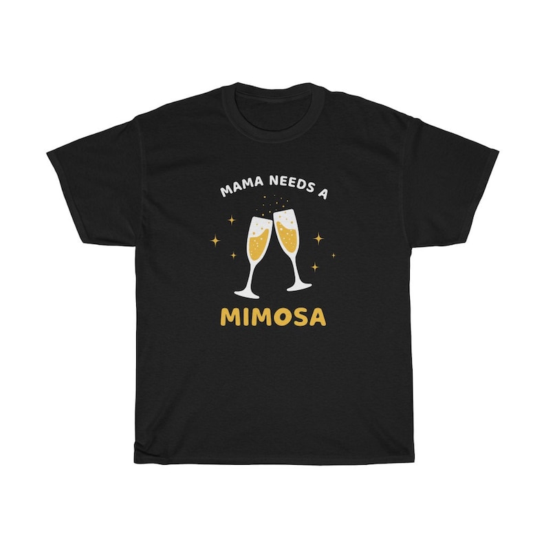 May include: Black t-shirt with the text "MAMA NEEDS A MIMOSA" in white and gold. The design features two champagne flutes with bubbly drinks and gold stars. A fun and casual tee for a relaxed vibe.