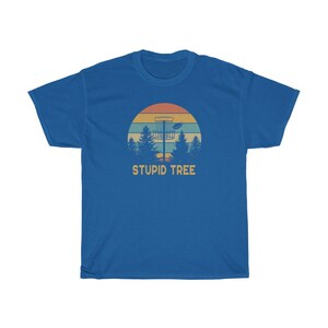 Pode incluir: Camiseta azul com um design retr&ocirc; de disc golf. O gr&aacute;fico inclui uma cesta de disc golf, &aacute;rvores e um p&ocirc;r do sol. O texto "STUPID TREE" &eacute; impresso abaixo. Uma camiseta casual para jogadores de disc golf.