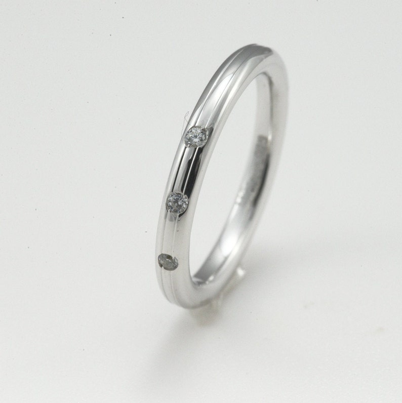 May include: A simple silver band ring with three small diamonds set into the band.
