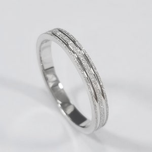 May include: A silver wedding band with two rows of small, sparkling diamonds.