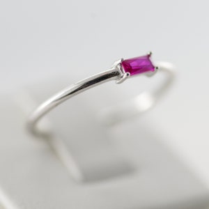 May include: A silver ring with a single, rectangular, pink gemstone.