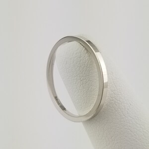 May include: A silver band ring with a flat, wide profile. The ring is marked "14k" on the inside.
