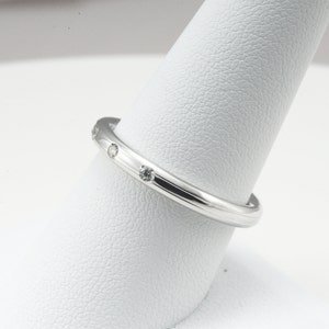May include: A thin silver band with small diamonds set into the metal.