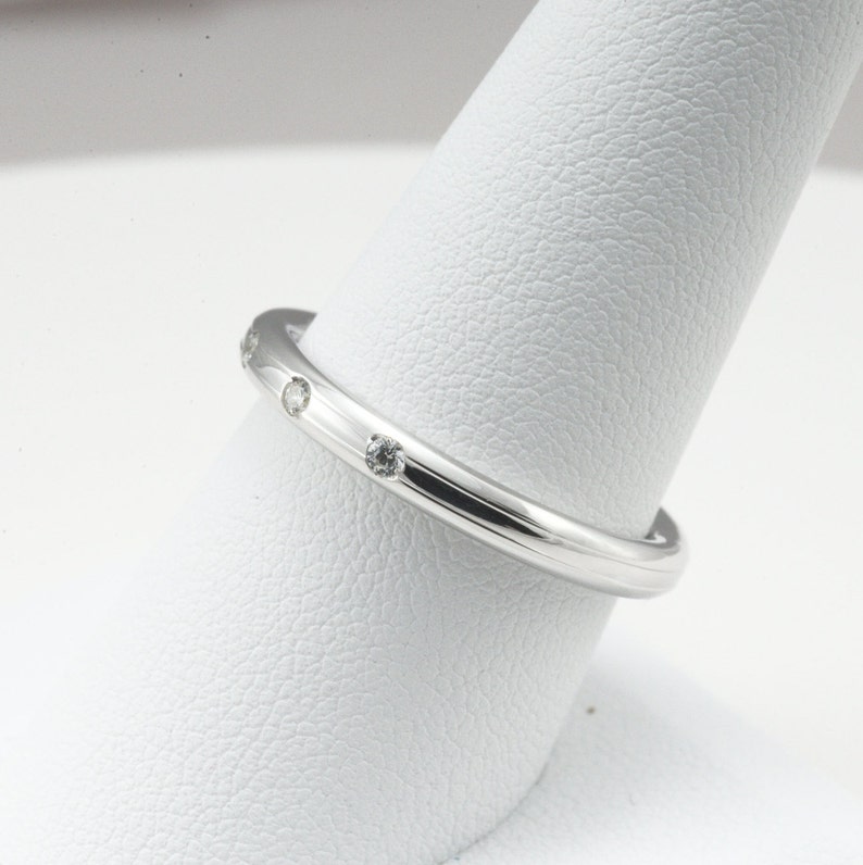 May include: A thin silver band with small diamonds set into the metal.