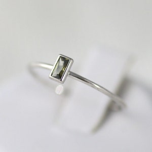 May include: A silver ring with a small, rectangular, dark green gemstone.