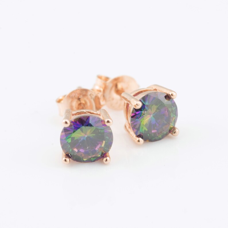 May include: A pair of rose gold stud earrings with iridescent round gemstones.