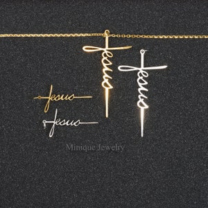 May include: A set of four gold and silver Jesus cross pendants. The pendants are in the shape of a cross with the word "Jesus" written in cursive on the cross. The pendants are on a black background.