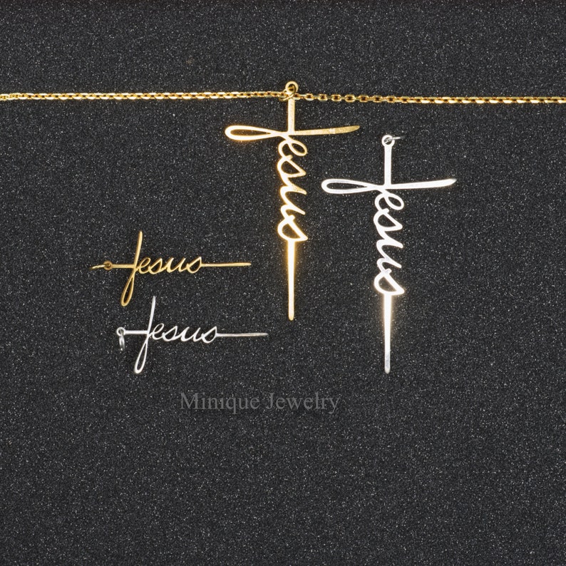 May include: A set of four gold and silver Jesus cross pendants. The pendants are in the shape of a cross with the word "Jesus" written in cursive on the cross. The pendants are on a black background.