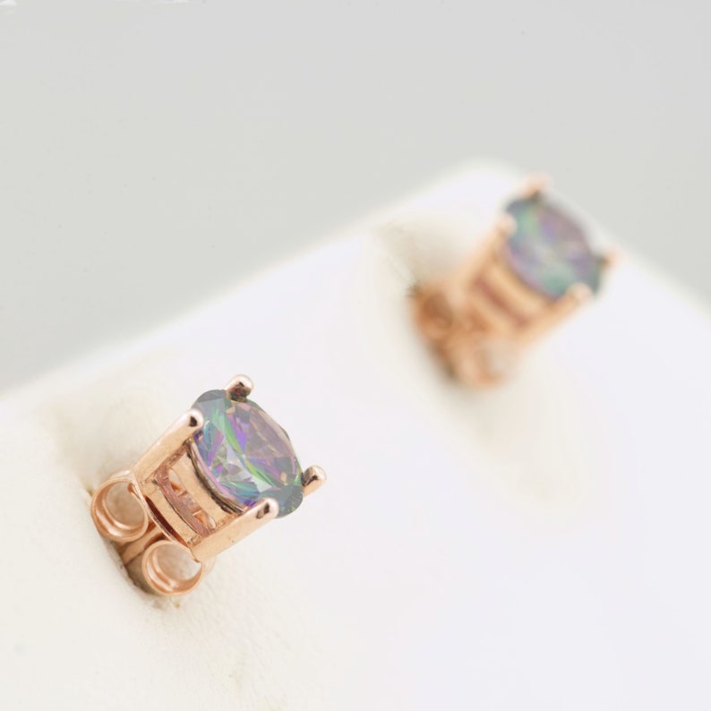 May include: A pair of rose gold stud earrings with iridescent round gemstones.