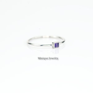 May include: A delicate silver ring with a small square-shaped amethyst gemstone.