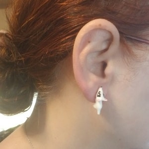 May include: White ceramic earrings shaped like a small dog with black eyes and nose.
