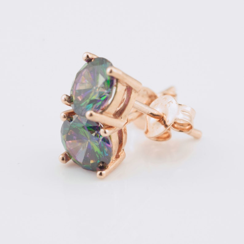 May include: A pair of gold stud earrings with iridescent round gemstones. The earrings have a post and butterfly back.