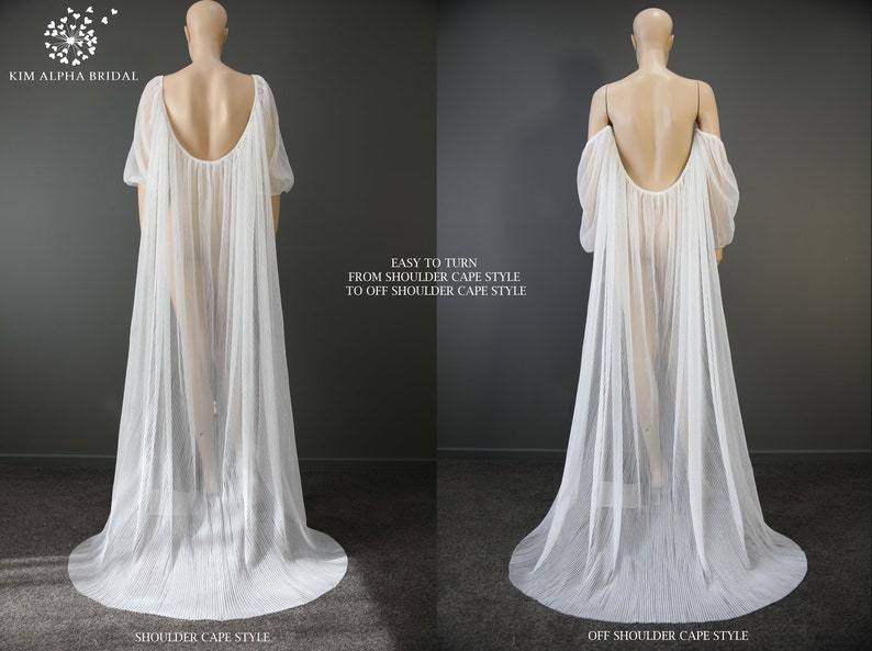 May include: A white bridal cape with a flowing design, shown in two styles: shoulder cape and off-shoulder cape. The cape features long sleeves and a pleated skirt. Text on the image reads "EASY TO TURN FROM SHOULDER CAPE STYLE TO OFF SHOULDER CAPE STYLE."