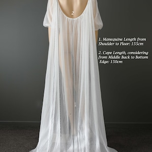 May include: A white, pleated bridal cape on a mannequin. The cape has short sleeves and a low back. The mannequin length from shoulder to floor is 155cm, and the cape length is 150cm. The Kim Alpha Bridal logo is visible.