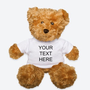 May include: A brown teddy bear wearing a white t-shirt with the text "YOUR TEXT HERE" printed on it.