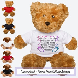 May include: A brown teddy bear wearing a white t-shirt with a pink and blue heart design and the text "Here's a special hug between us two. So you are always with me and I am always with you. Grandma".