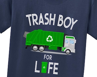 May include: A navy blue t-shirt featuring a graphic of a green garbage truck with a white recycling symbol. The text reads TRASH BOY FOR LIFE, with a green trash bin replacing the letter I in the word LIFE, printed in white lettering.