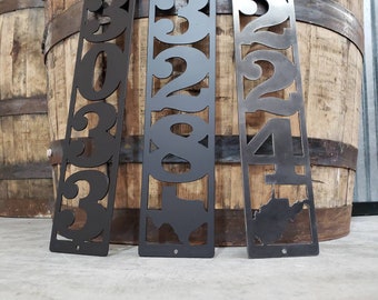 May include: Three metal house number signs with black paint. The numbers are 303, 328, and 224. The signs are on a wooden background.