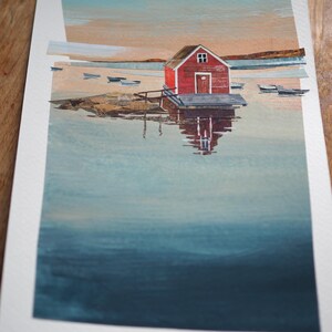 Puede incluir: Pintura a la acuarela de una caseta de botes roja en un muelle, reflejada en el agua. La obra representa una escena costera serena con peque&ntilde;as embarcaciones y una colorida puesta de sol. La pintura est&aacute; sobre papel blanco.