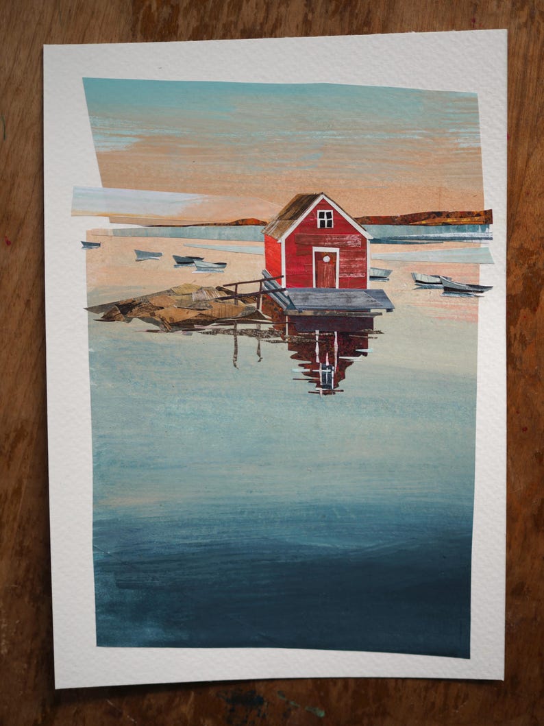 Puede incluir: Pintura a la acuarela de un cobertizo rojo para botes en un muelle, con peque&ntilde;os botes en el agua. El cielo es una mezcla de naranja, azul y blanco. El agua refleja el cobertizo y el cielo. La pintura est&aacute; sobre papel blanco.