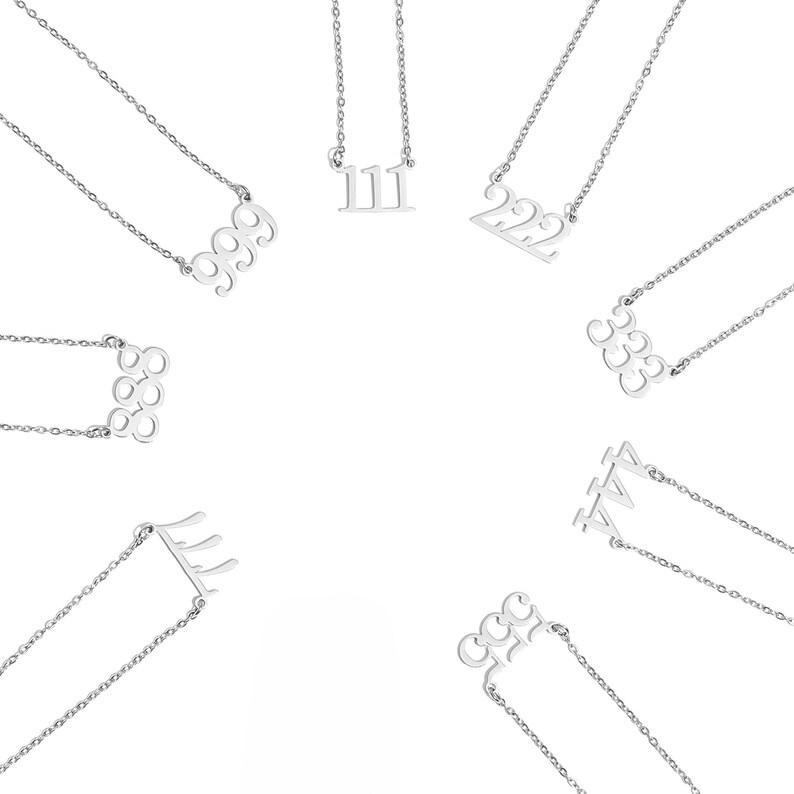 Op de afbeelding: Een verzameling zilverkleurige kettingen, elk met een nummerhanger. De nummers 111, 222, 333, 444, 555 en 999 zijn zichtbaar. De kettingen worden gepresenteerd tegen een witte achtergrond.
