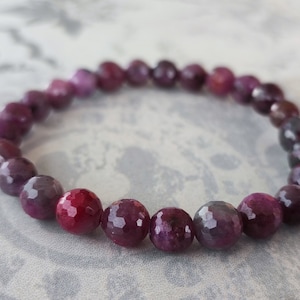 Könnte beinhalten: Ein Armband aus facettierten violetten und rosafarbenen Edelsteinperlen.