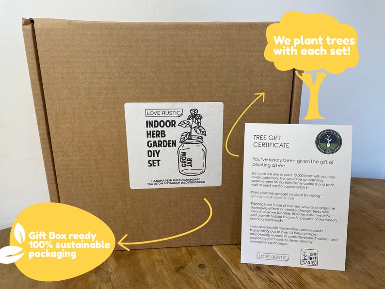 May include: A brown cardboard box with a white label that says "Love Rustic Indoor Herb Garden DIY Set". The box is sitting on a wooden table. A white card with the text "Tree Gift Certificate" is next to the box. The card says "You've kindly been given the gift of planting a tree." The card also has a logo that says "One Tree Planted".