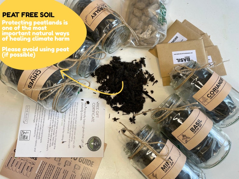 May include: Six glass jars filled with peat-free soil, labelled with different herbs: Chives, Parsley, Basil, Coriander, and Mint. Each jar is tied with twine and includes a small brown paper bag with seeds. The image includes a yellow sign that reads "PEAT FREE SOIL" and a message about protecting peatlands.
